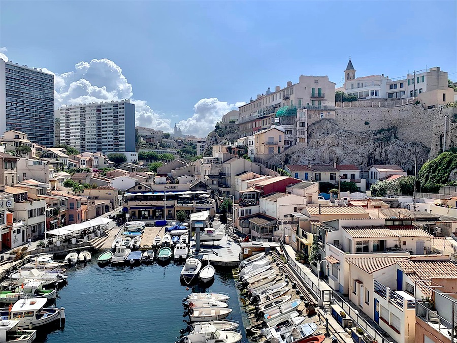 petit port empli de petits bateaux. Autour, petites maisons.