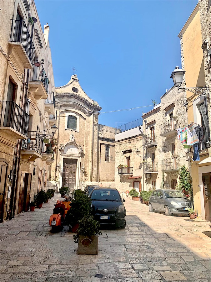 placette entourée de maisons de pierre et une petite église au fond, à Bari, Italie