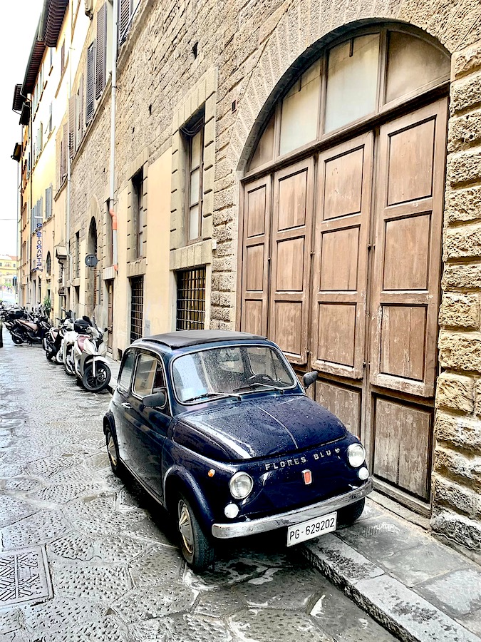 vieille Fiat 500 bleu marine stationnée à cheval sur le trottoir d'une rue à Florence, Italie