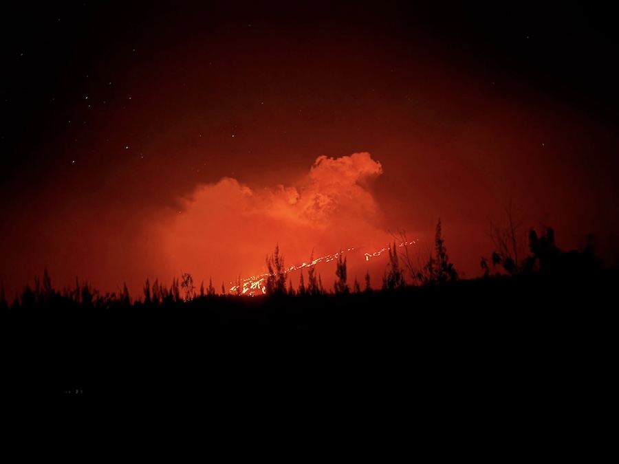 Depuis le parking, ciel rougeoyant et lave incandescente visible à travers les nuages de vapeur