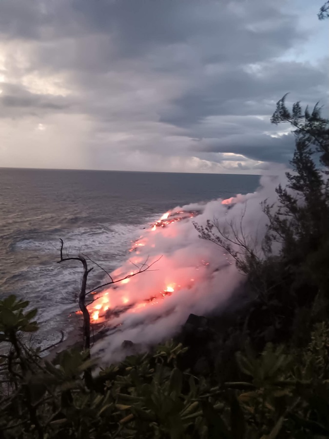 La lave incandescente atteint la mer provoquant des nuages de vapeur au bord de l'eau, alors que le jour commence à poindre